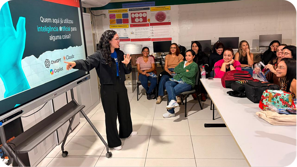 Formadora aponta para uma tela interativa com a pergunta “Quem aqui já utilizou inteligência artificial para alguma coisa?” diante de professoras