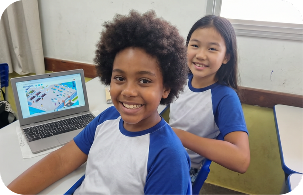 Duas alunas sorridentes ao lado de um notebook com um cenário da Plataforma OLO na tela